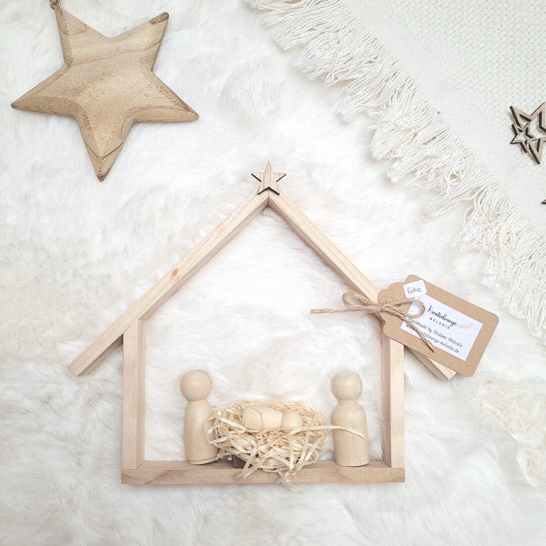 Weihnachtskrippe aus Holz mit Holzfiguren und Stern auf weißem Untergrund