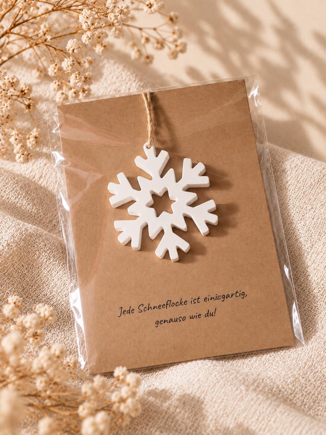 Schneeflocken-Anhänger an Kraftpapierkarte mit Spruch